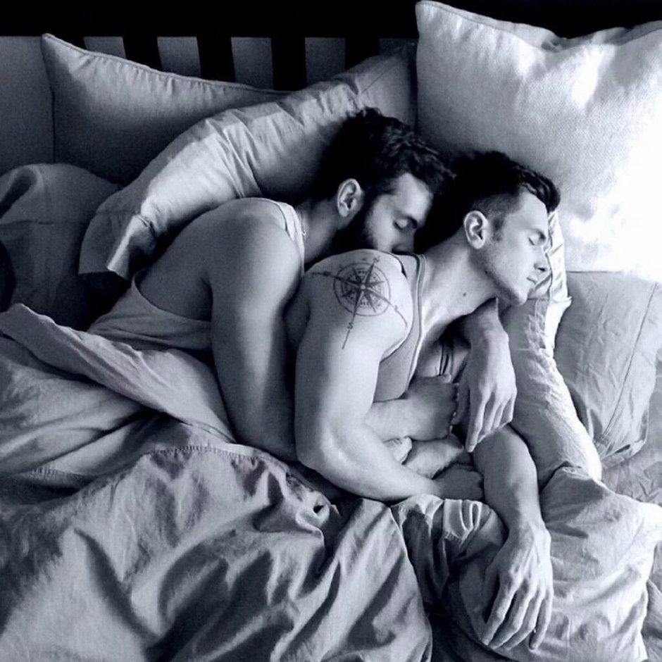 Two men hug in bed