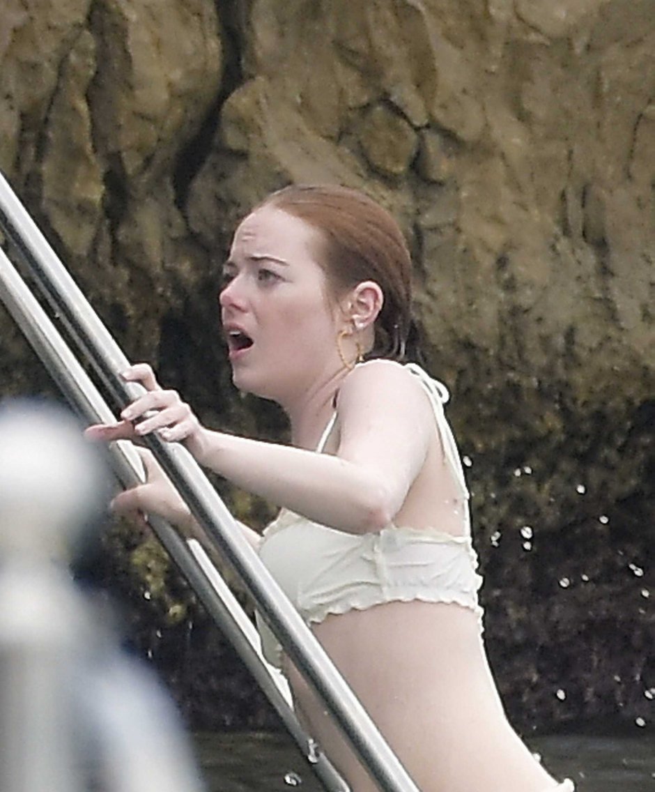 Emma Stone sits on the bed