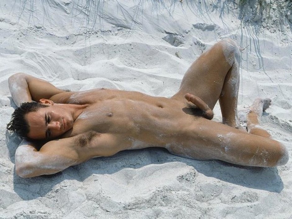 A naked guy lies on the beach