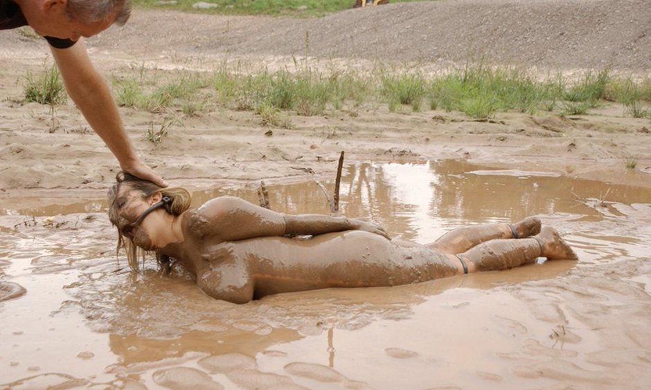 Naked women are lying in mud