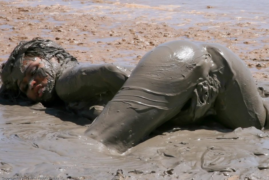 The girl is lying in the mud nude