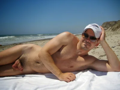 Голый парень лежит на пляже