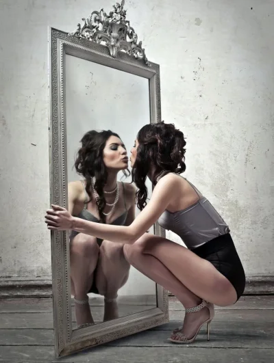 Женщина смотрится в зеркало
