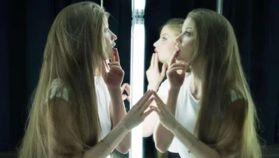 Девушка смотрится в зеркало