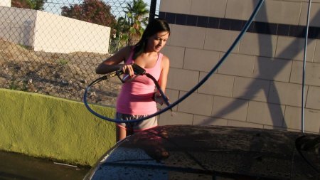 Girl washes a car in swimsuit